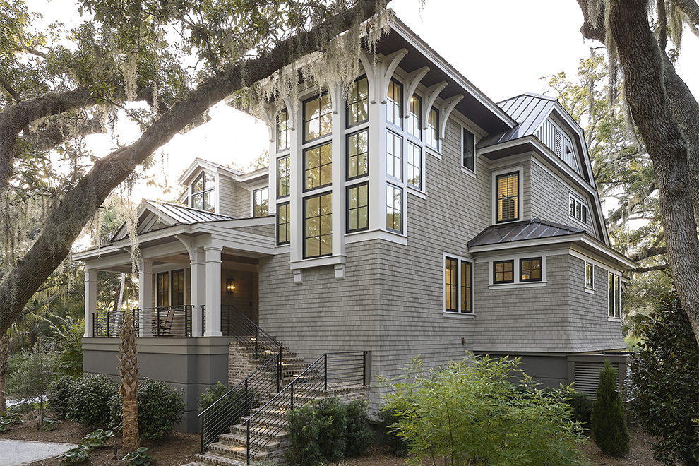 Nature-inspired custom home on Kiawah Island framed by oak trees, featuring coastal shingle siding and detailed architectural elements by Marc Camens.