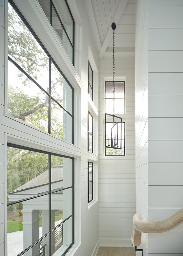 Tall vertical windows fill a stairwell with natural light, showcasing intentional window placement in the architectural design process by Camens Architectural Group.