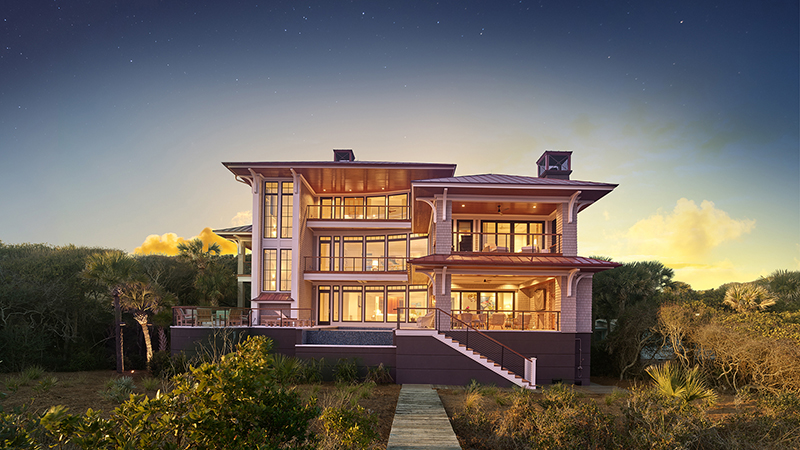 Custom coastal home with illuminated window placement highlights intentional design and the interplay of light and architecture.