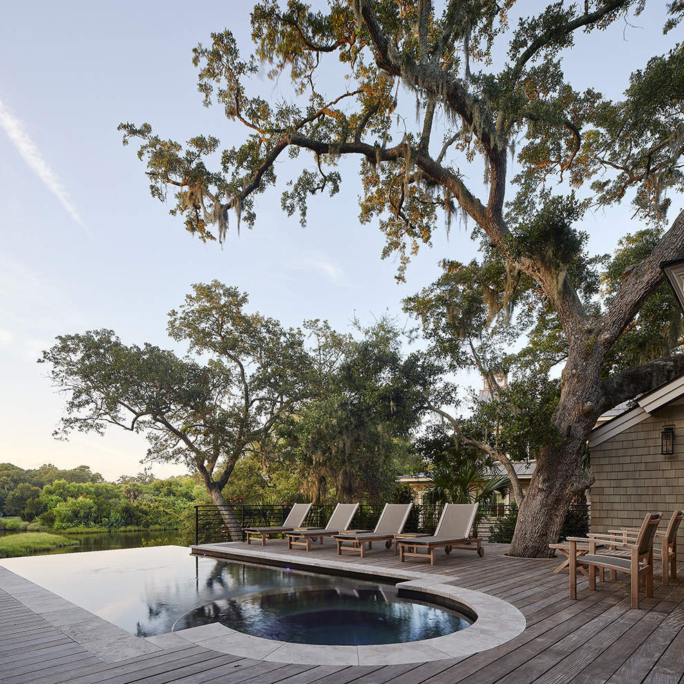 Pool deck design framed by live oak trees, showing how residential architecture and pool design connect with natural surroundings.